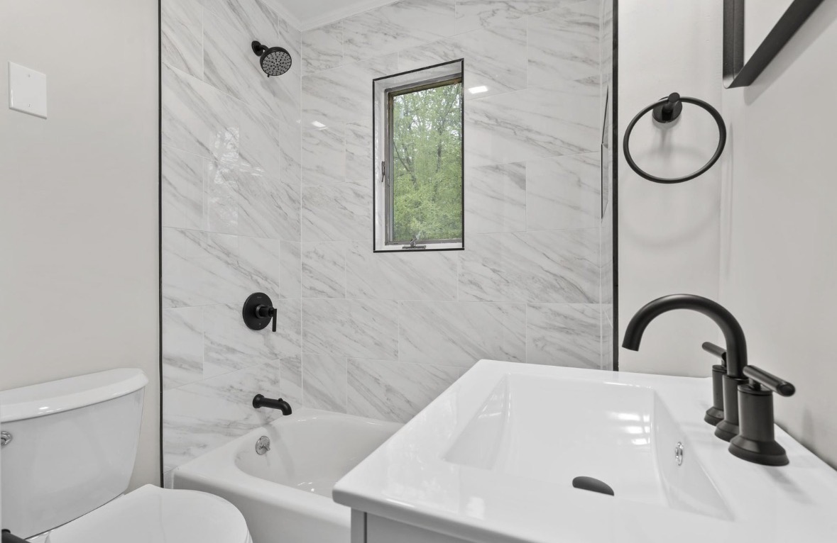 Renovated bathroom with marble tile shower surround and black fixtures