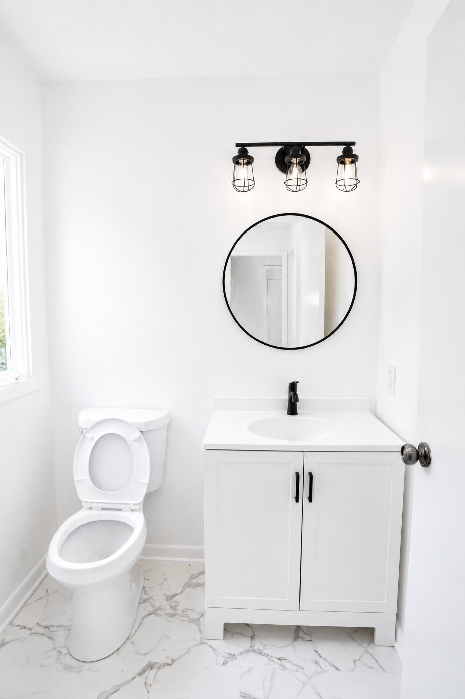 Renovated powder room with round black-framed mirror