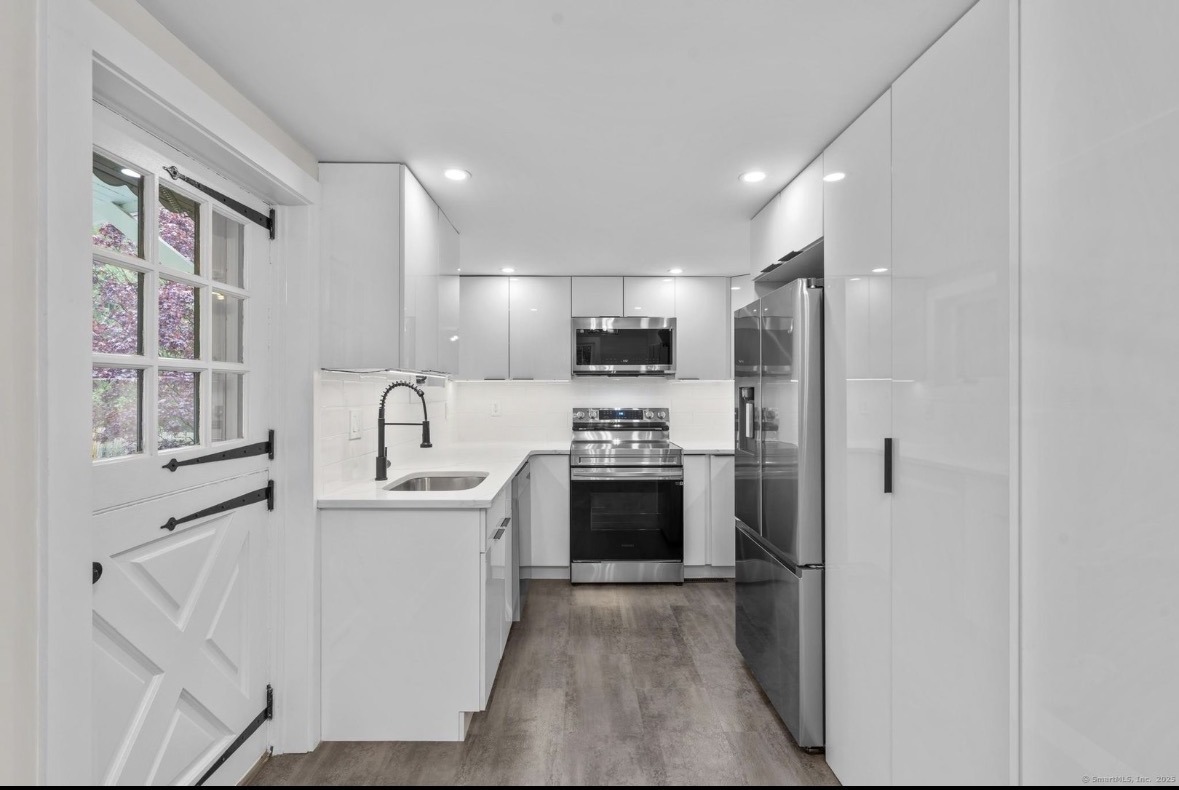 Renovated kitchen with white cabinets, stainless appliances, and a farmhouse door