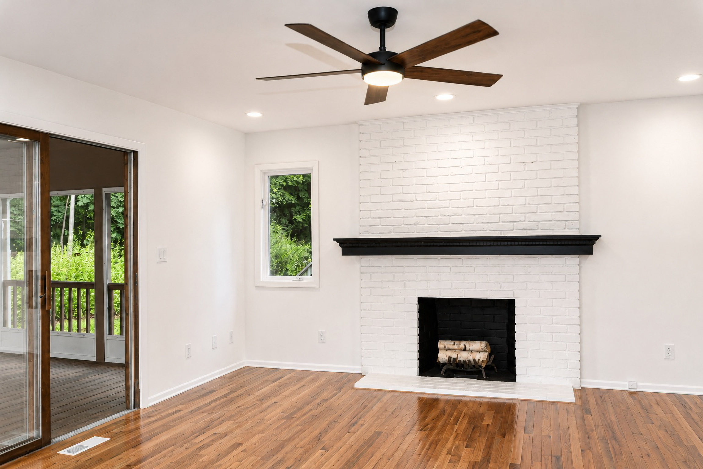 Renovated living room with white brick fireplace and black mantle